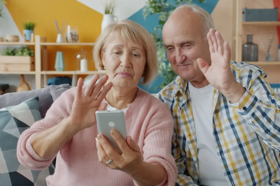 Seniorenpaar winkt beim Videoanruf mit der Familie